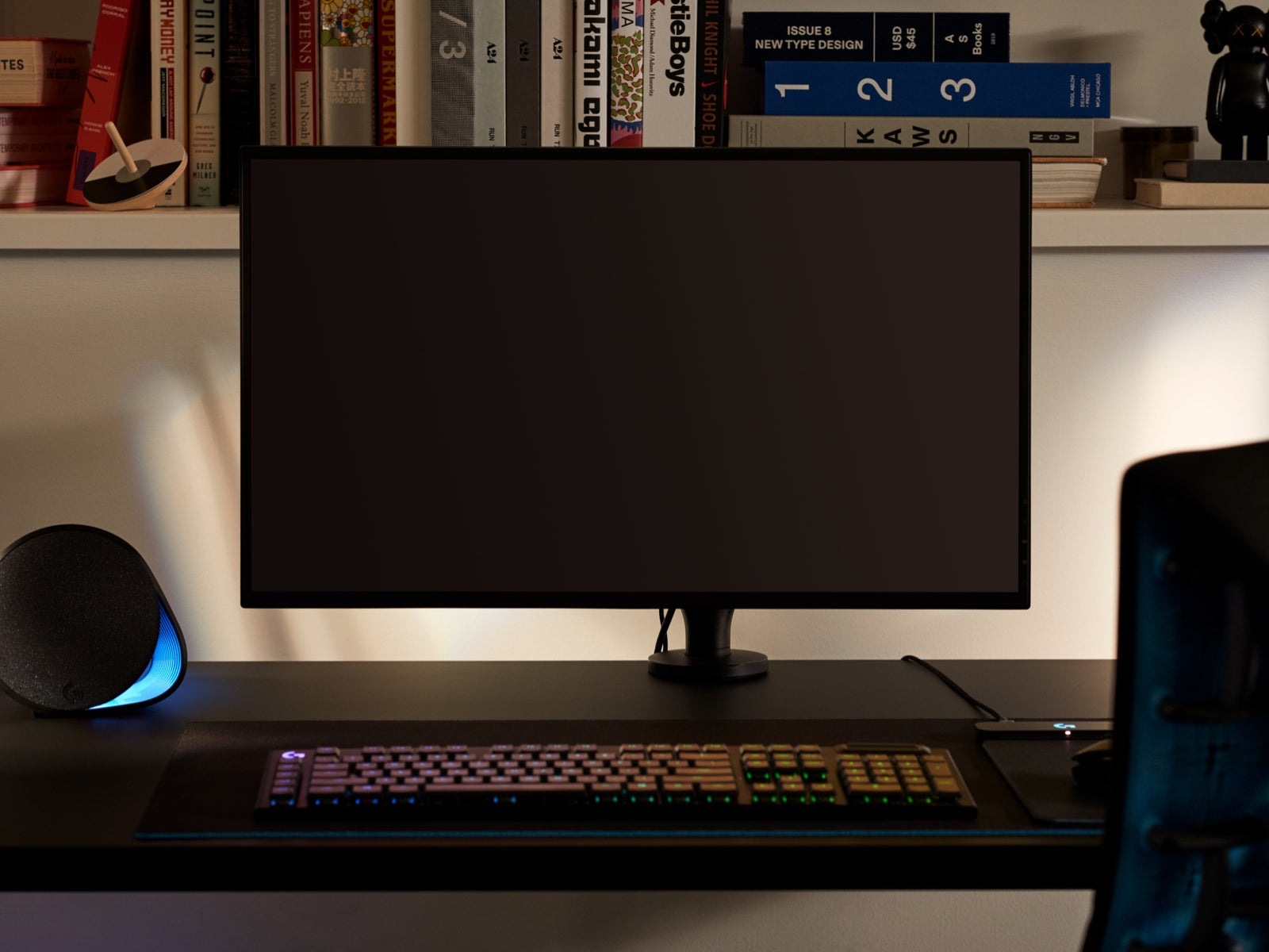 Un grande monitor, a rappresentare che il braccio porta monitor Ollin può sorreggere schermi di ogni dimensione, è collocato sul braccio sopra una scrivania con una tastiera in primo piano e oggetti su un ripiano in secondo piano.